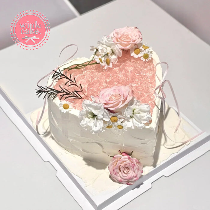Heart-shaped birthday cake decorated with pink flowers.