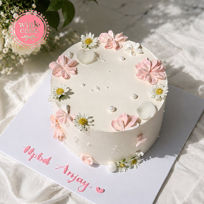 White birthday cake with delicate pastel rose decorations.