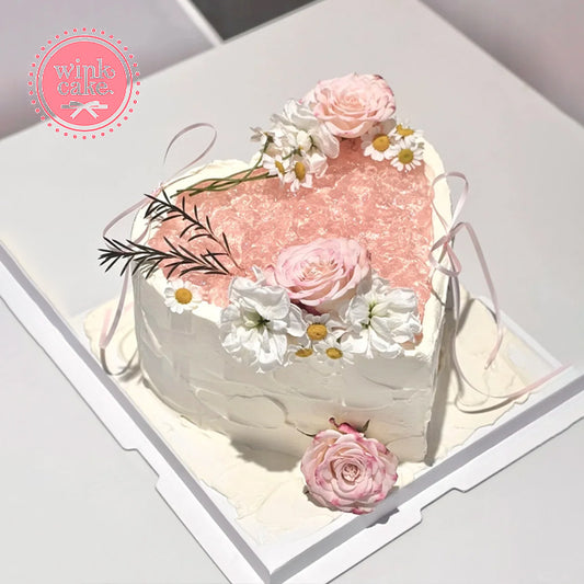 Heart-shaped birthday cake decorated with pink flowers.