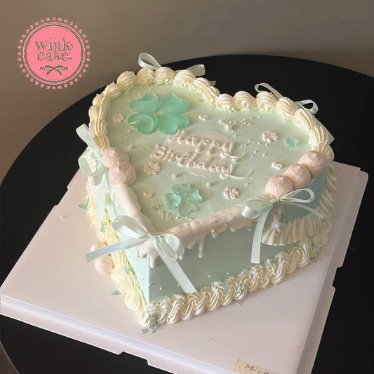 Feminine turquoise heart-shaped cake with four-leaf clovers – a gift for a young girl.