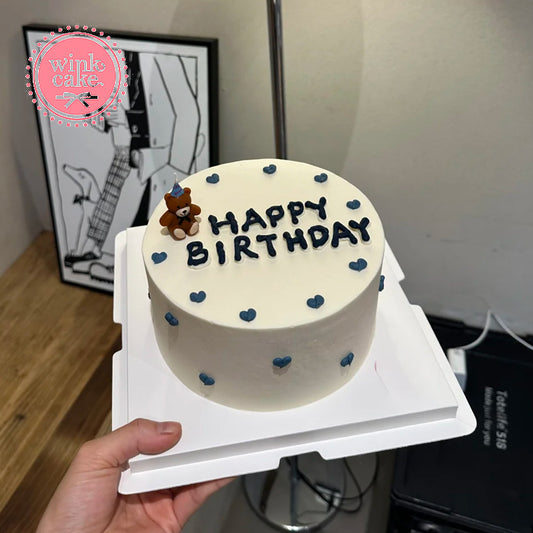 Một chiếc bánh sinh nhật hình trái tim với nến hình gấu bông.